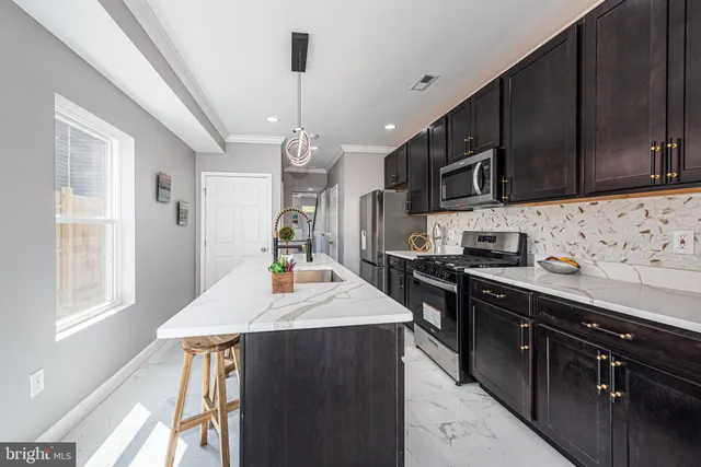 a kitchen with stainless steel appliances kitchen island granite countertop a sink a stove and a refrigerator