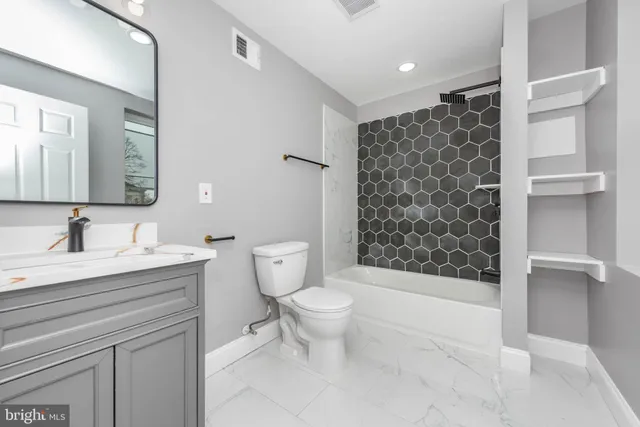 a bathroom with a granite countertop sink a toilet and a mirror