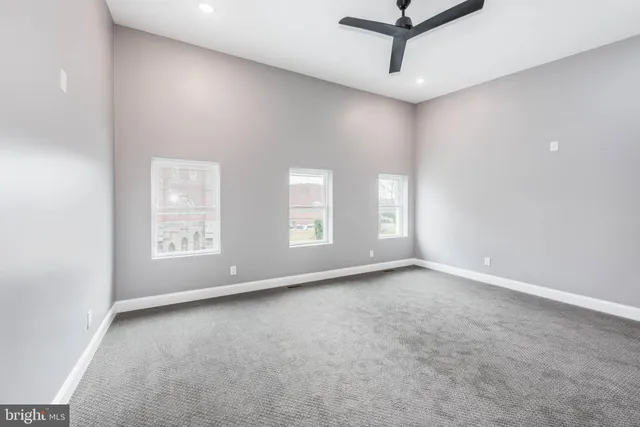 an empty room with windows and fan