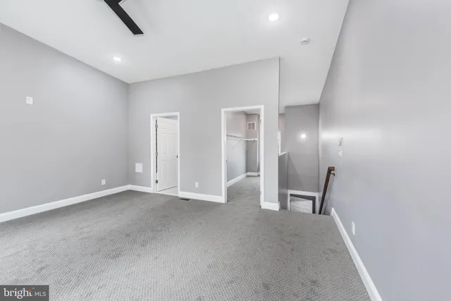 an empty room with mirror and a bathroom