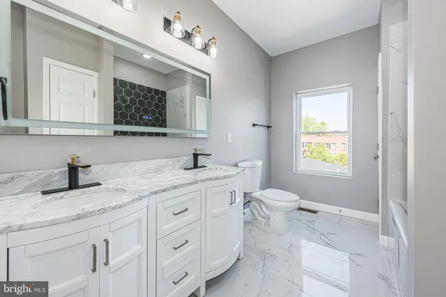 a bathroom with a granite countertop sink mirror and a toilet
