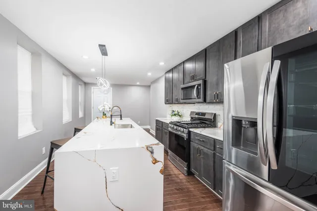 a kitchen with kitchen island a counter top space stainless steel appliances and cabinets