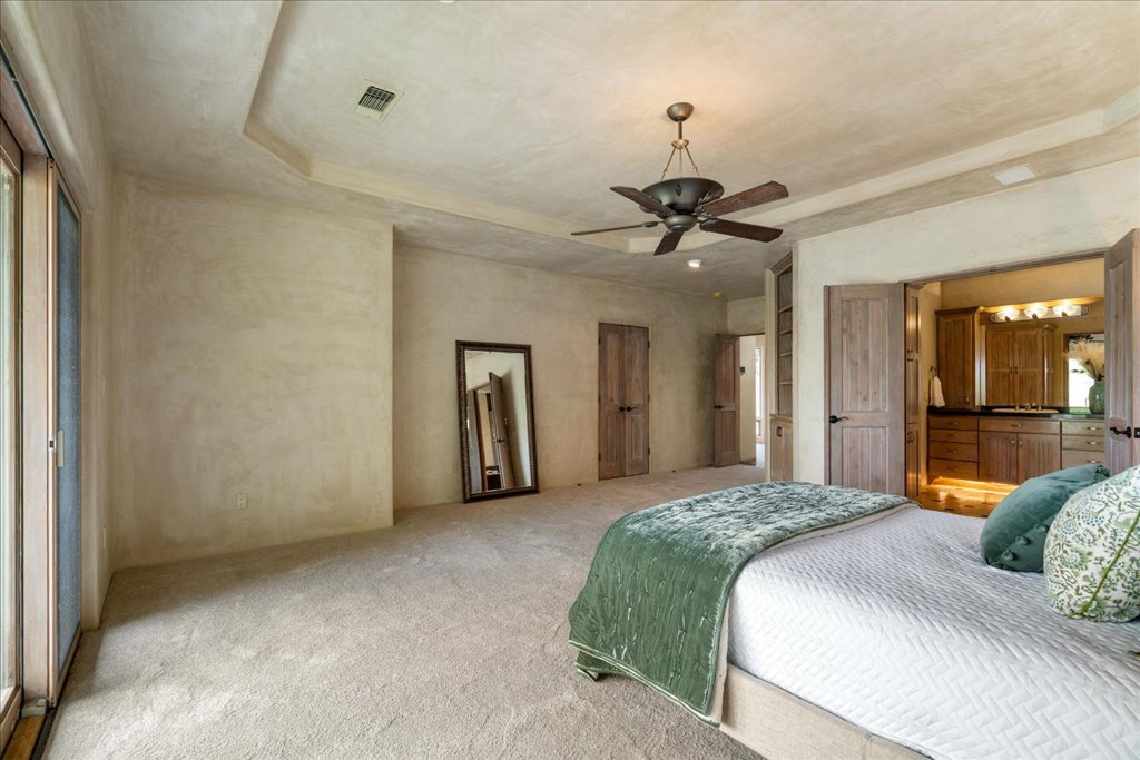 24736 Travis Lakeside Cove, Unit A Spicewood, TX 78669 - Photo 15 of 36 a bedroom with a bed and a chandelier