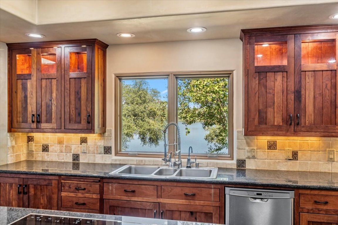 24736 Travis Lakeside Cove, Unit A Spicewood, TX 78669 - Photo 32 of 36 a kitchen with granite countertop a sink and a window