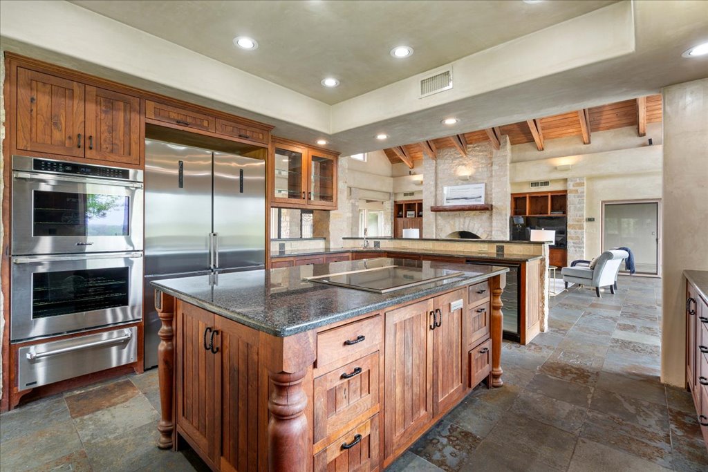 24736 Travis Lakeside Cove, Unit A Spicewood, TX 78669 - Photo 6 of 36 a kitchen with stainless steel appliances granite countertop a stove a sink and a refrigerator