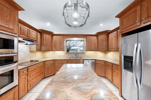 a large kitchen with stainless steel appliances granite countertop a large counter top stove a sink dishwasher and microwave