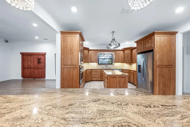 a kitchen with stainless steel appliances granite countertop a refrigerator and a stove top oven