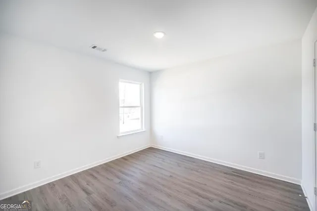 an empty room with wooden floor and window