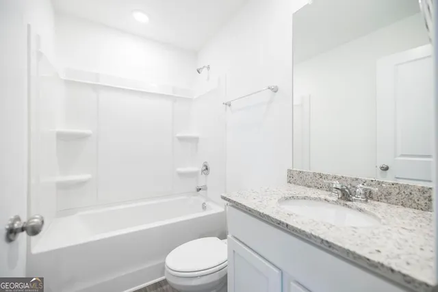 a bathroom with a granite countertop sink a toilet and bathtub