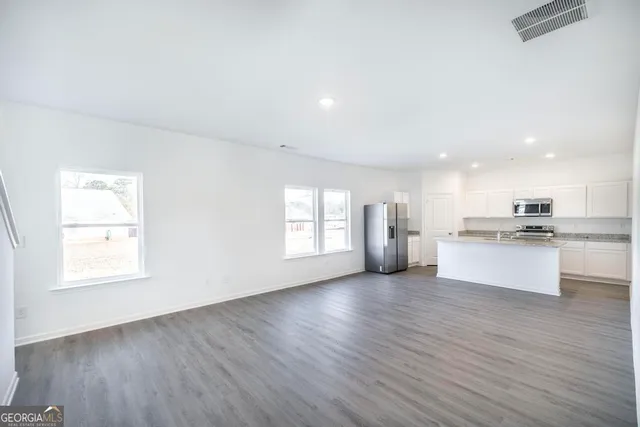 a view of kitchen with granite countertop cabinets stainless steel appliances with wooden floor and windows
