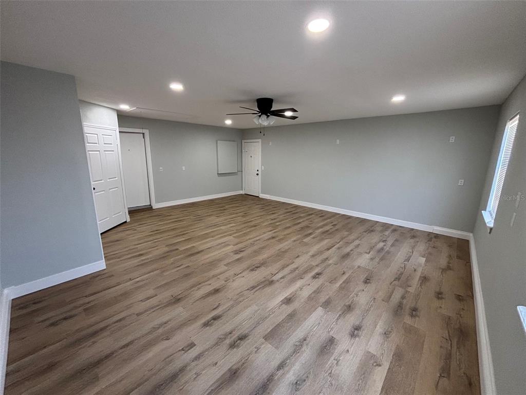 9801 Southeast Sunset Harbor Road Summerfield, FL 34491 - Photo 21 of 37 an empty room with wooden floor and a ceiling fan