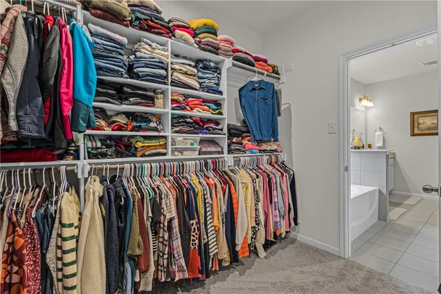 a view of walk in closet with clothes and shoes