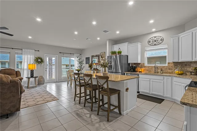 a kitchen with stainless steel appliances granite countertop a table and chairs in it