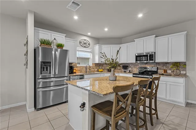 a kitchen with kitchen island white cabinets and stainless steel appliances