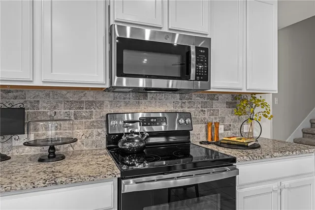 a kitchen with granite countertop a stove top oven microwave and cabinets