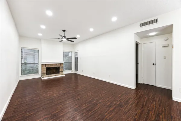 a view of an empty room with wooden floor fireplace and a window