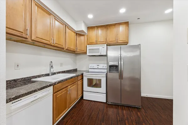 a kitchen with stainless steel appliances granite countertop a sink a stove a refrigerator and cabinets