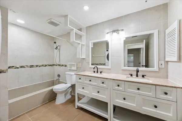 a bathroom with a double vanity sink a toilet a mirror and shower