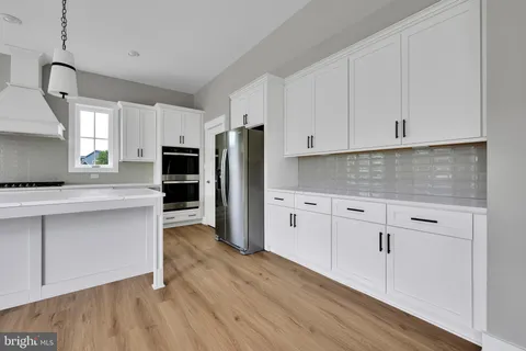 a kitchen with white cabinets and stainless steel appliances