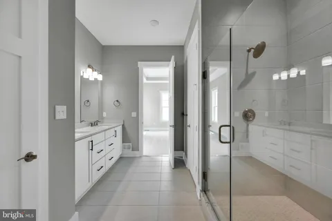 a bathroom with a double vanity sink a toilet a mirror and shower