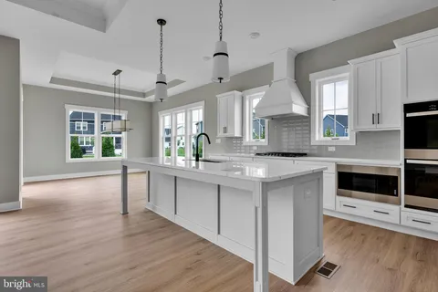 a kitchen with stainless steel appliances kitchen island granite countertop a stove a sink and a wooden floor