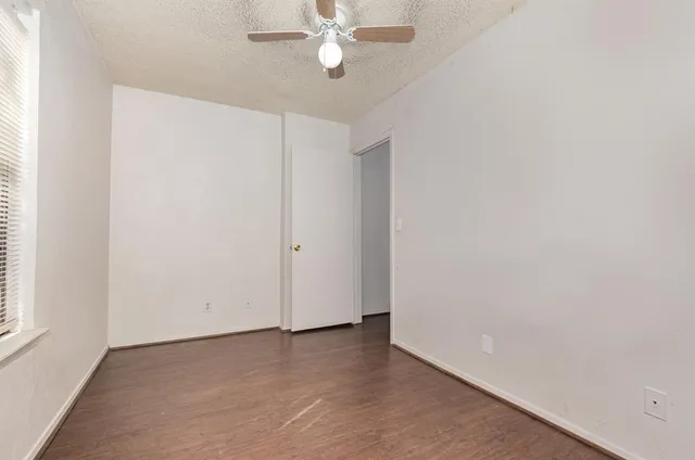 an empty room with a window and a ceiling fan