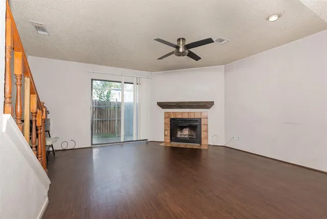 a view of an empty room with wooden floor fireplace and a window