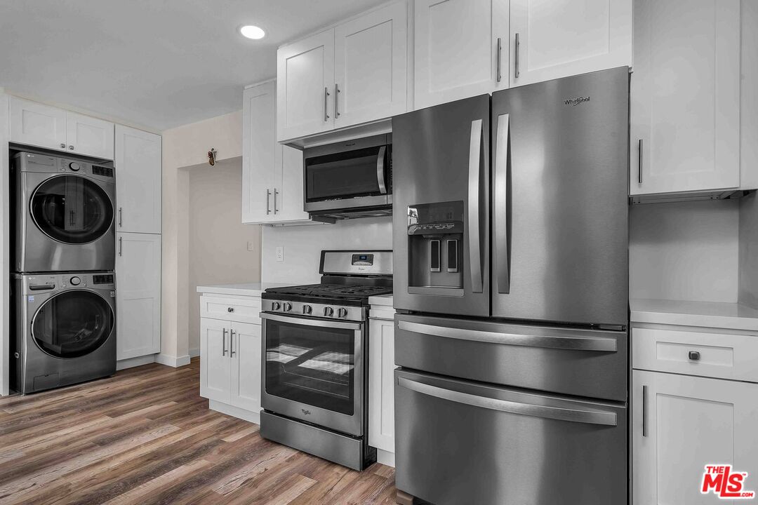 11575 Riverside Drive Valley Village, CA 91602 - Photo 5 of 16 a kitchen with stainless steel appliances a refrigerator a stove and white cabinets