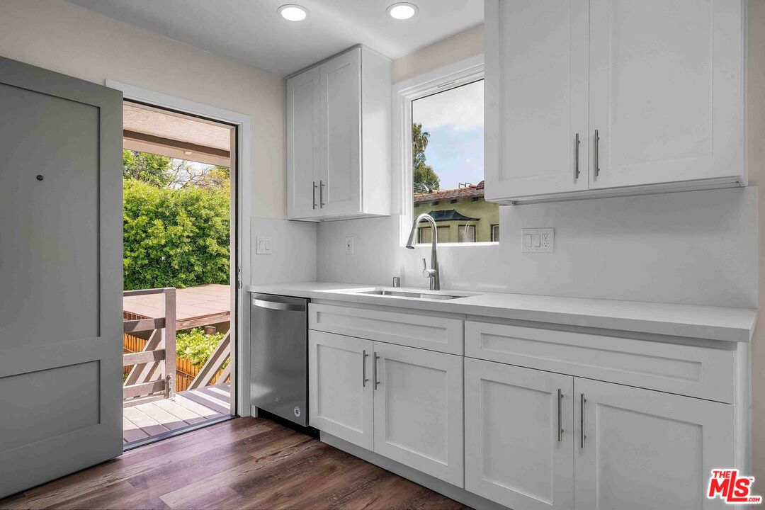 11575 Riverside Drive Valley Village, CA 91602 - Photo 6 of 16 a kitchen with wooden cabinets a sink a window and wooden floor