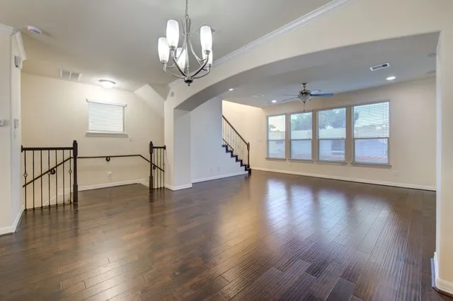 a view of an empty room with wooden floor and a chandelier