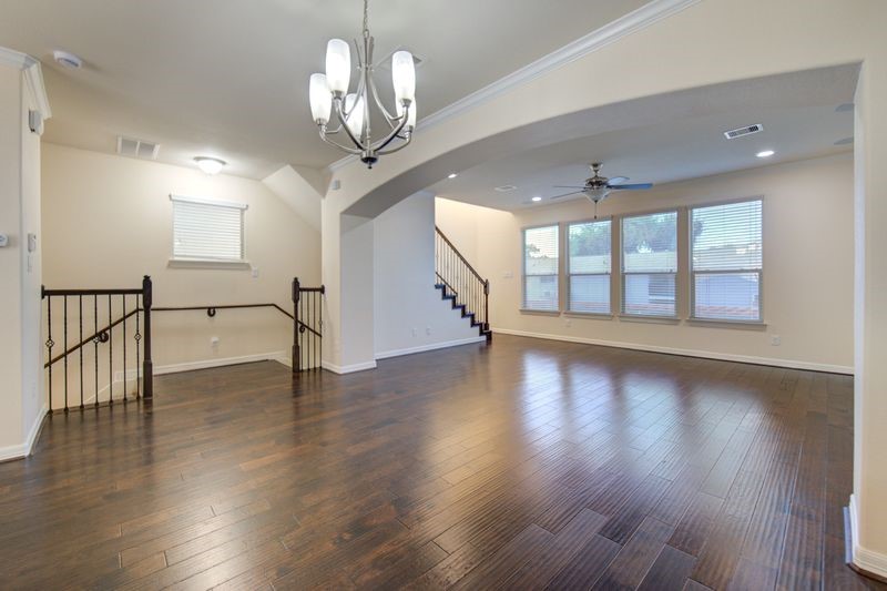 10014 Spring Shadows Park Circle Houston, TX 77080 - Photo 14 of 39 a view of an empty room with wooden floor and a chandelier