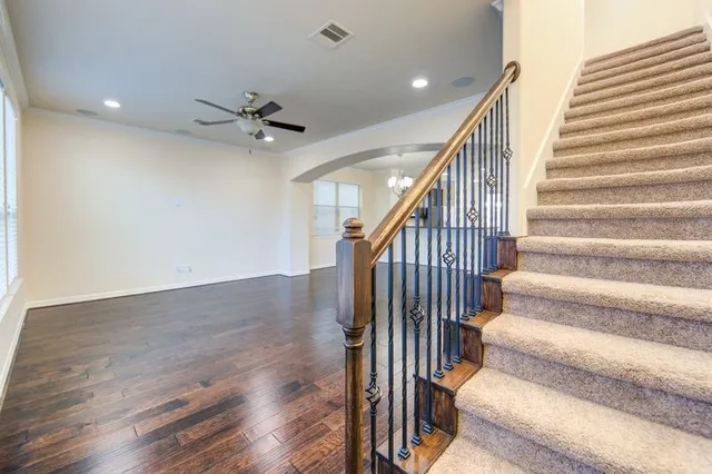 a view of staircase with wooden floor and a ceiling fan