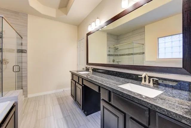 a bathroom with a granite countertop sink a mirror and a shower