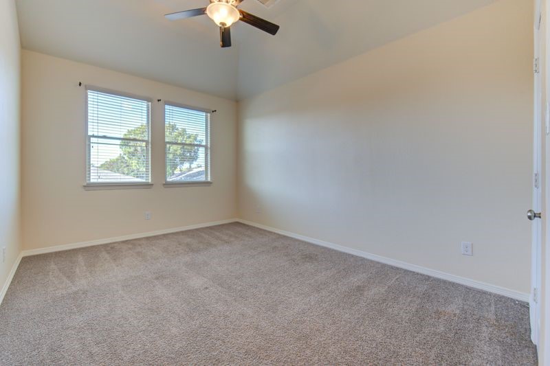 10014 Spring Shadows Park Circle Houston, TX 77080 - Photo 25 of 39 an empty room with a chandelier fan and windows