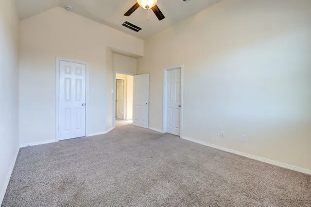 an empty room with chandelier fan and windows