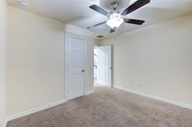 an empty room with a chandelier fan and a ceiling fan