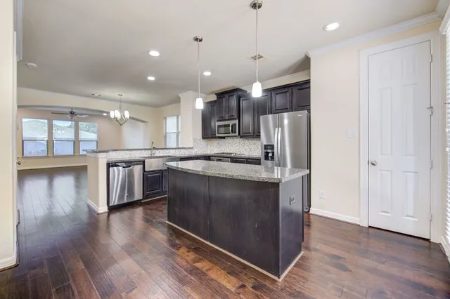 a kitchen with stainless steel appliances granite countertop a refrigerator a sink a stove and a wooden floors