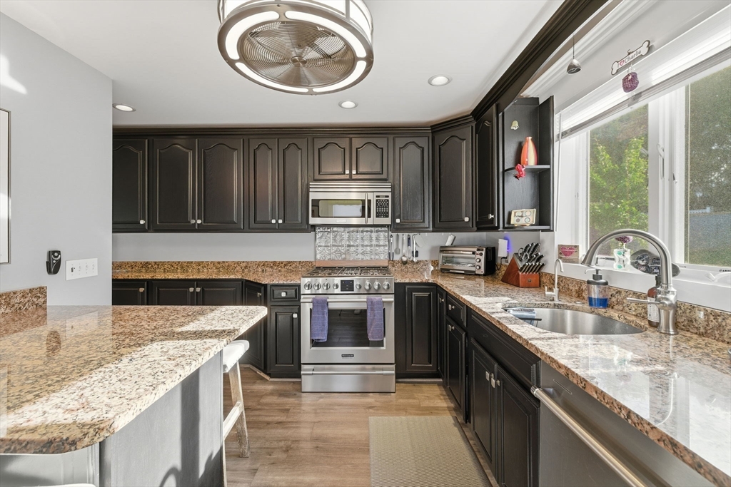 5 West Kenneth Street Lawrence, MA 01843 - Photo 15 of 41 a kitchen with kitchen island granite countertop a sink stove and cabinets