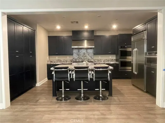 a kitchen with kitchen island granite countertop a refrigerator and a stove top oven