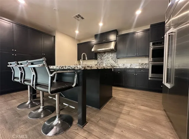 a kitchen with stainless steel appliances granite countertop a sink counter space and chairs