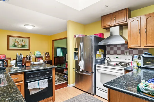a kitchen with stainless steel appliances granite countertop a stove refrigerator and cabinets