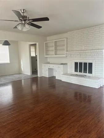 a view of an empty room with wooden floor and a ceiling fan