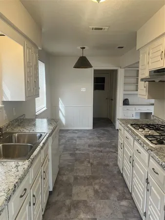 a kitchen with granite countertop a sink stove and cabinets