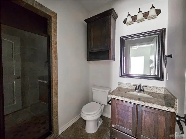 a bathroom with a granite countertop toilet sink and mirror