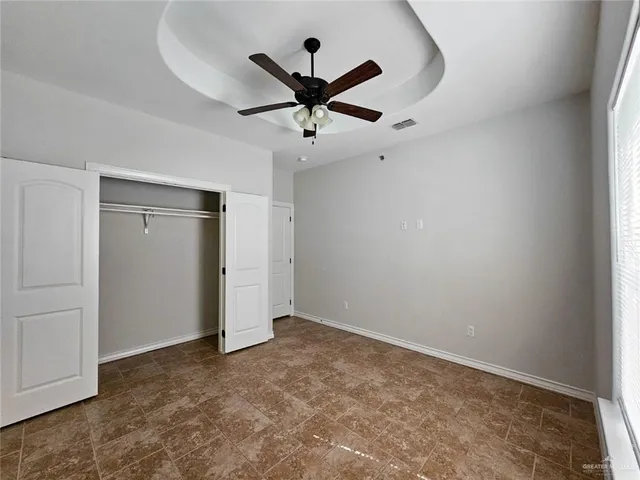 an empty room with ceiling fan and window