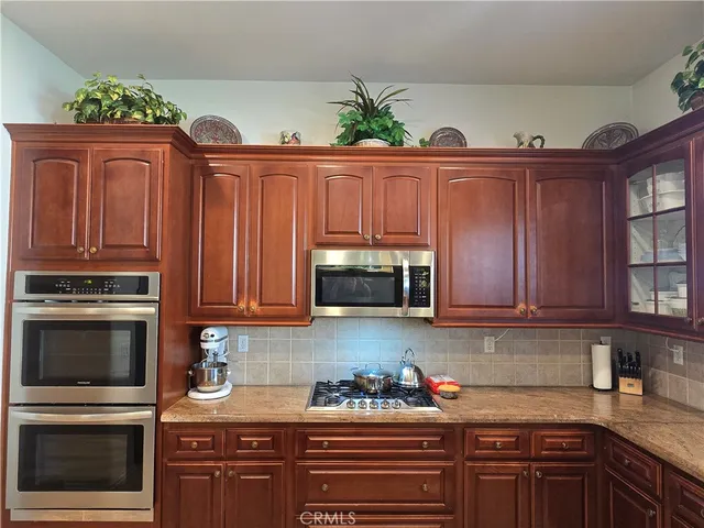 a kitchen with kitchen island granite countertop wooden cabinets stainless steel appliances and a window