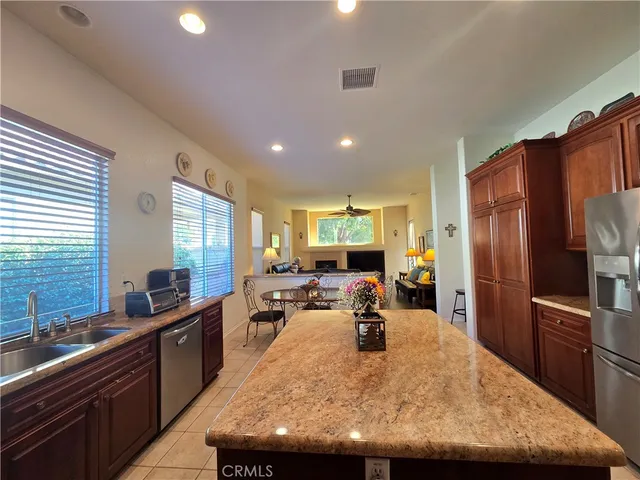 a kitchen with stainless steel appliances granite countertop a stove top oven a sink dishwasher a dining table and chairs with wooden floor