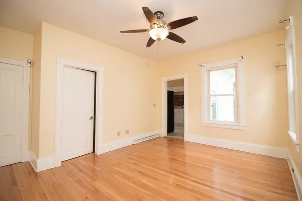 a view of an empty room with wooden floor and a window
