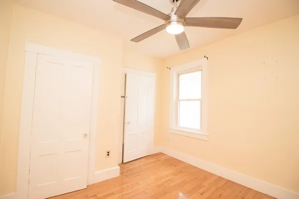 an empty room with a window and a ceiling fan