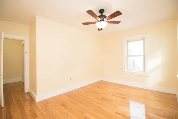 a view of a bedroom with wooden floor and a ceiling fan